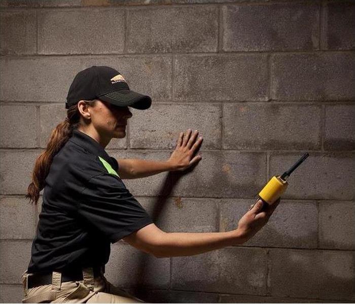 Servpro technician using tool to measure moisture in wall